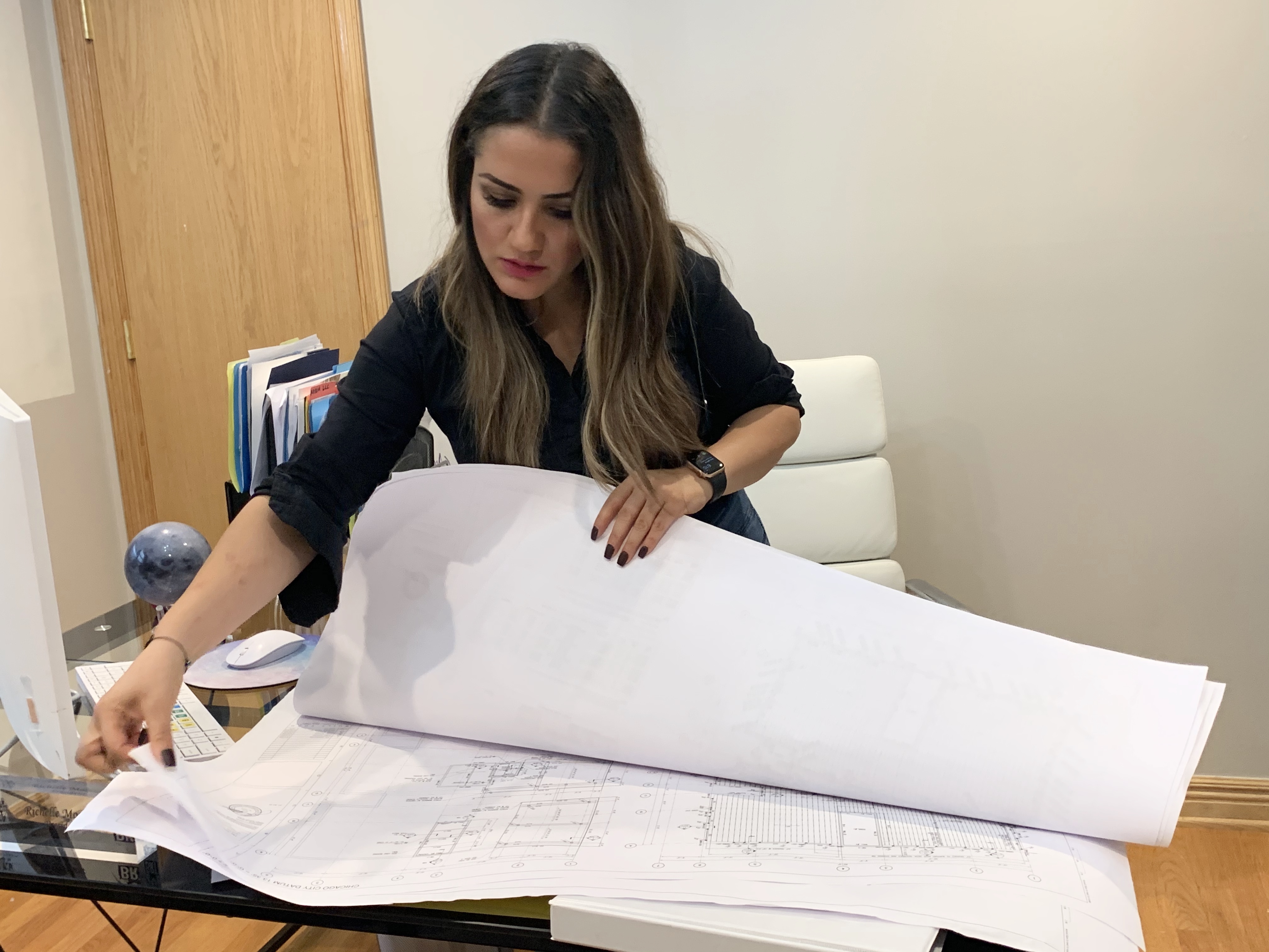 Richelle Moreno reviewing architectural blueprints at her office desk
