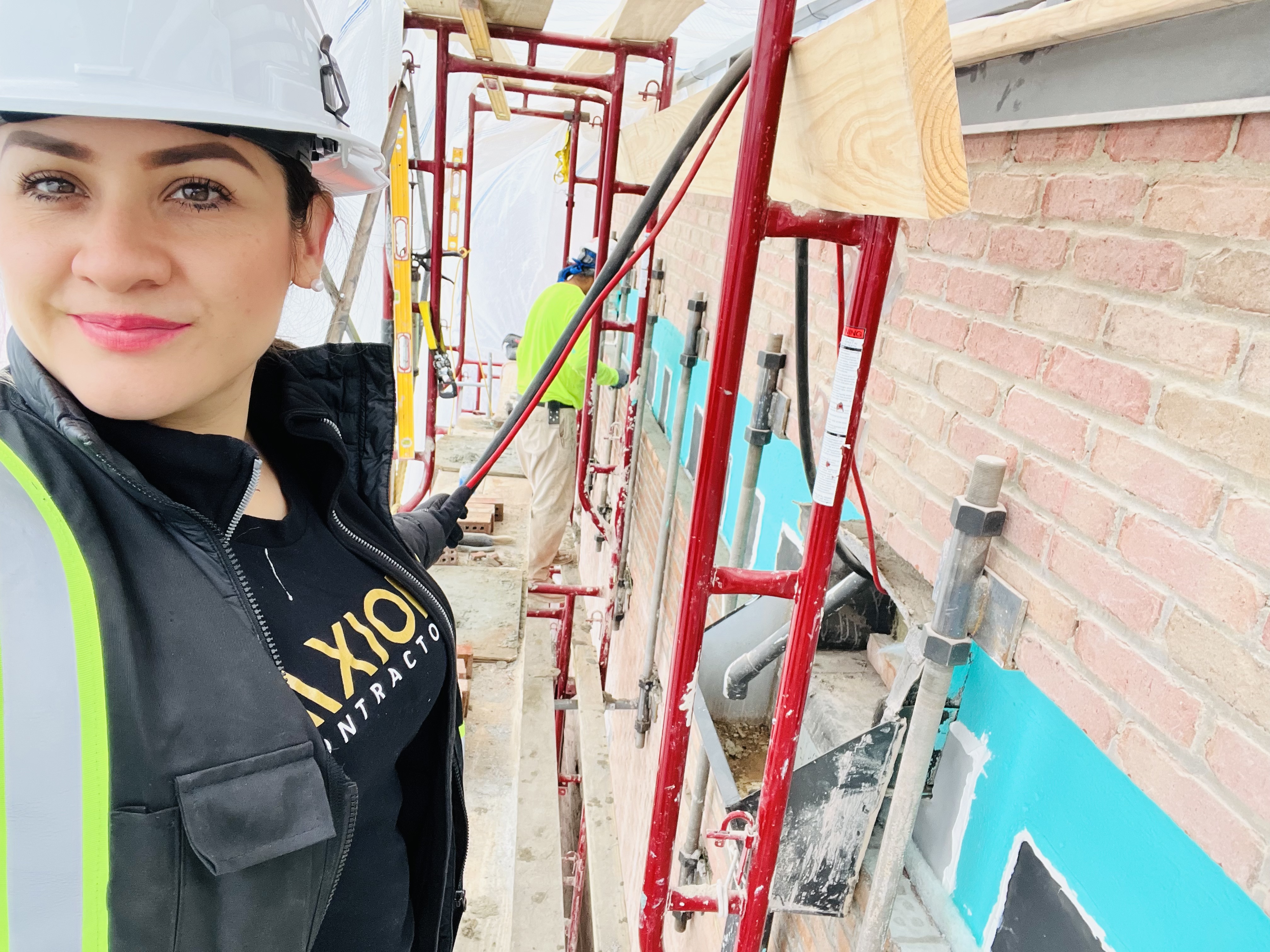 Richelle Moreno in an Axiom Contractors hard hat and vest on a masonry restoration job site